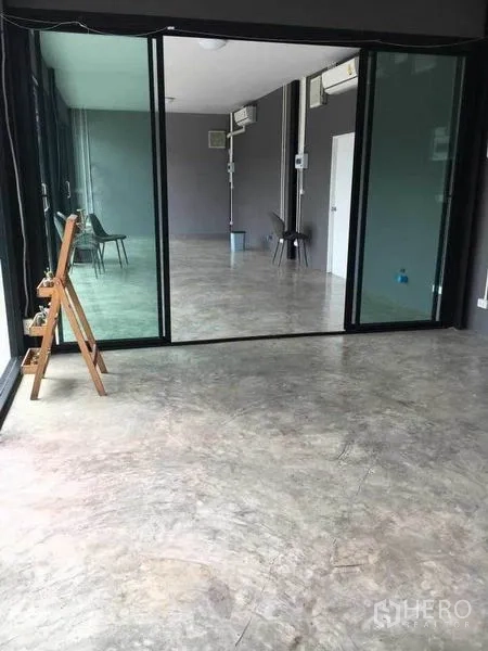 Home Office for rent in Din Daeng, Bangkok - Glass sliding partition dividing a bright concrete-floored workspace with AC and utility lines.