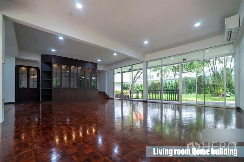 独立式住宅 出租在Khlong Toei, Bangkok - 宽敞客厅，深色木质壁柜与整面玻璃，面向花园