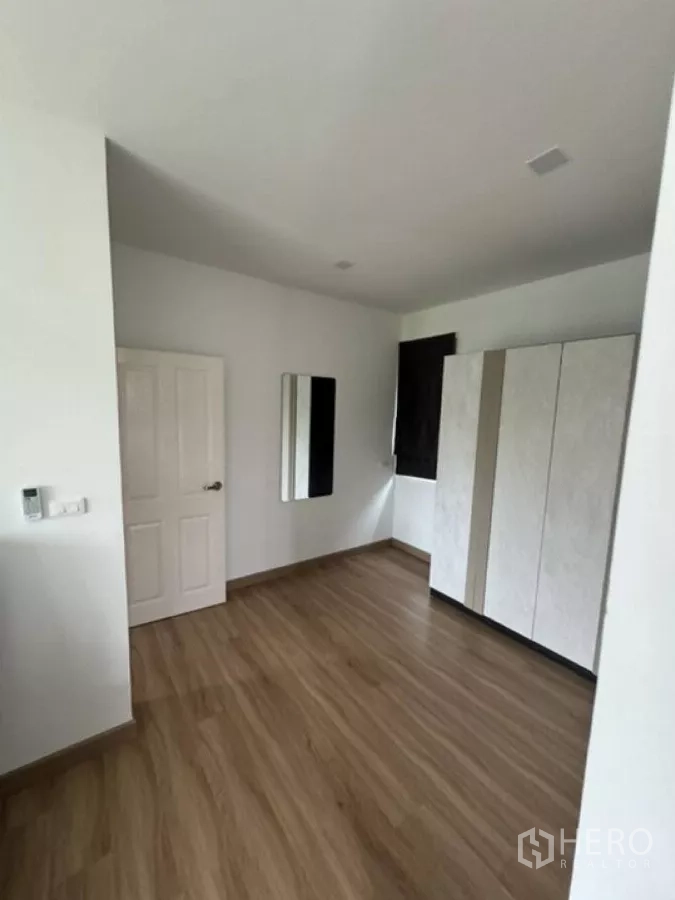 Detached House for rent in Thanyaburi, Pathum Thani - Spacious bedroom with wardrobes, wall mirror and wood-look flooring.