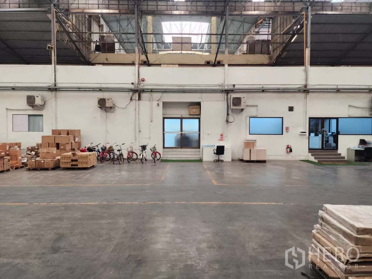 Factory for rent in Mueang Samut Sakhon, Samut Sakhon - Warehouse wall featuring office rooms, loading doors and stacked boxes.