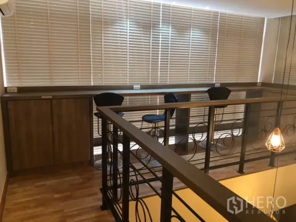คอนโด ขายในBang Na, Bangkok - ชั้นลอยเป็นมุมทำงาน เคาน์เตอร์บาร์ เก้าอี้สตูล ตู้ไม้ และราวโลหะข้างหน้าต่างสูง