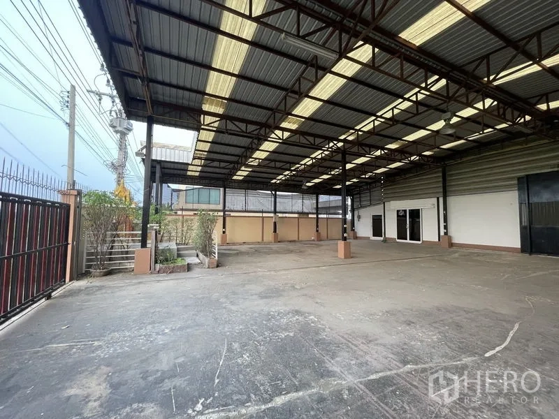Factory for rent in Lat Lum Kaeo, Pathum Thani - Covered loading bay under steel truss roof with secure fencing.
