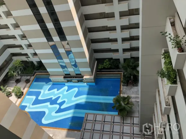 公寓 出租在Pathum Wan, Bangkok - 俯瞰公寓庭院泳池，蓝色几何图案水面与绿植环绕。