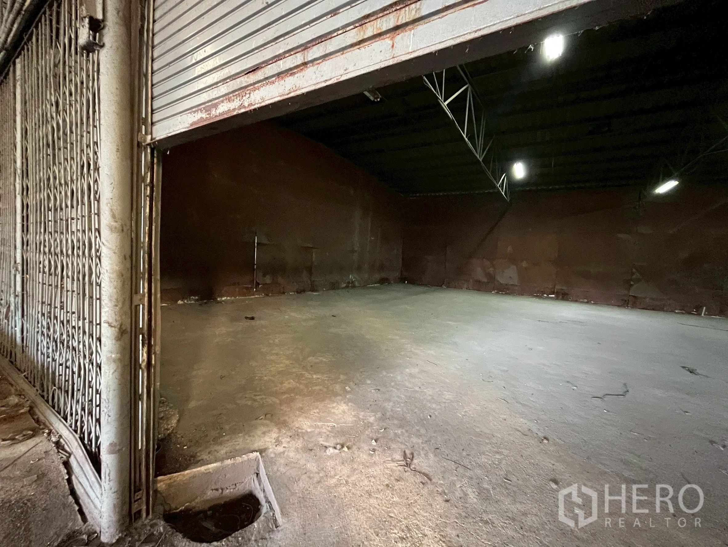Factory for rent in Phra Pradaeng, Samut Prakan - Storage bay with metal folding gate and roller door for secure goods keeping.