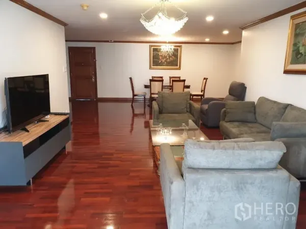 公寓 出租在Watthana, Bangkok - 宽敞的客餐厅，实木地板、灰色沙发、电视柜与水晶吊灯。