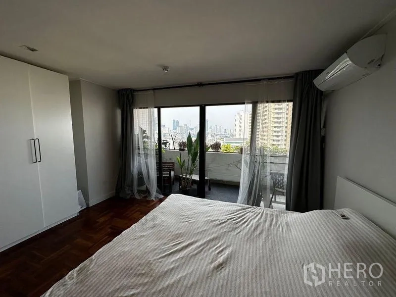 公寓 出租在Watthana, Bangkok - 主卧带衣柜与空调，阳台可观曼谷天际线。