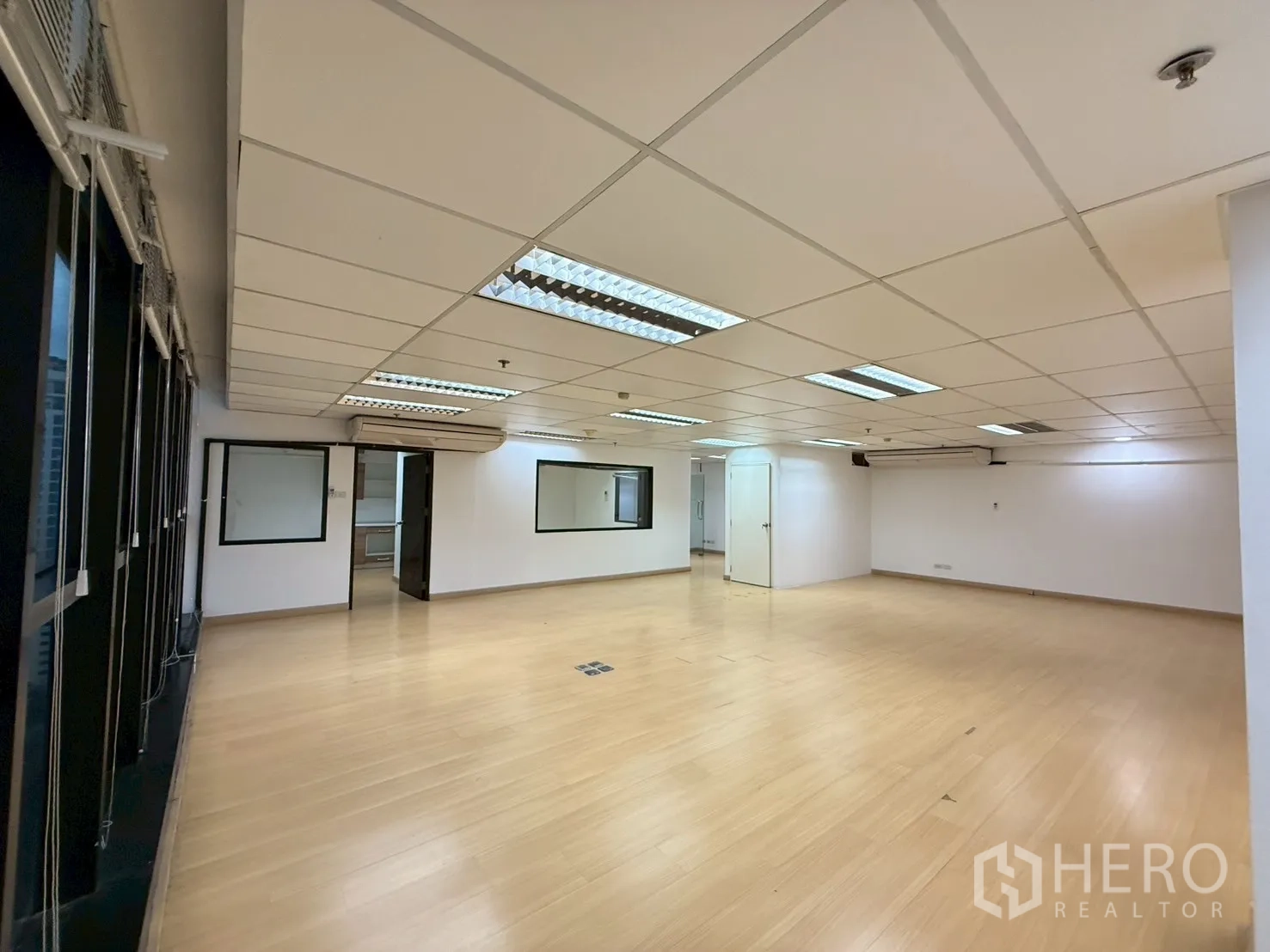 Office Space for rent in Watthana, Bangkok - Large open-plan office with drop ceiling lights, light wood flooring and internal windows.