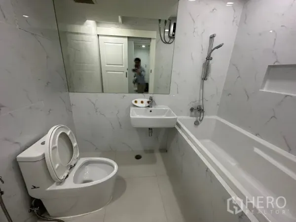 Condominium for rent in Watthana, Bangkok - Bathroom with bathtub, handheld shower, wall mirror and white tiles.