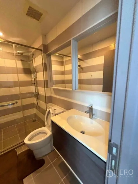 Condominium for rent or sale in Watthana, Bangkok - Bathroom with vanity, mirror, toilet and glass-enclosed shower.