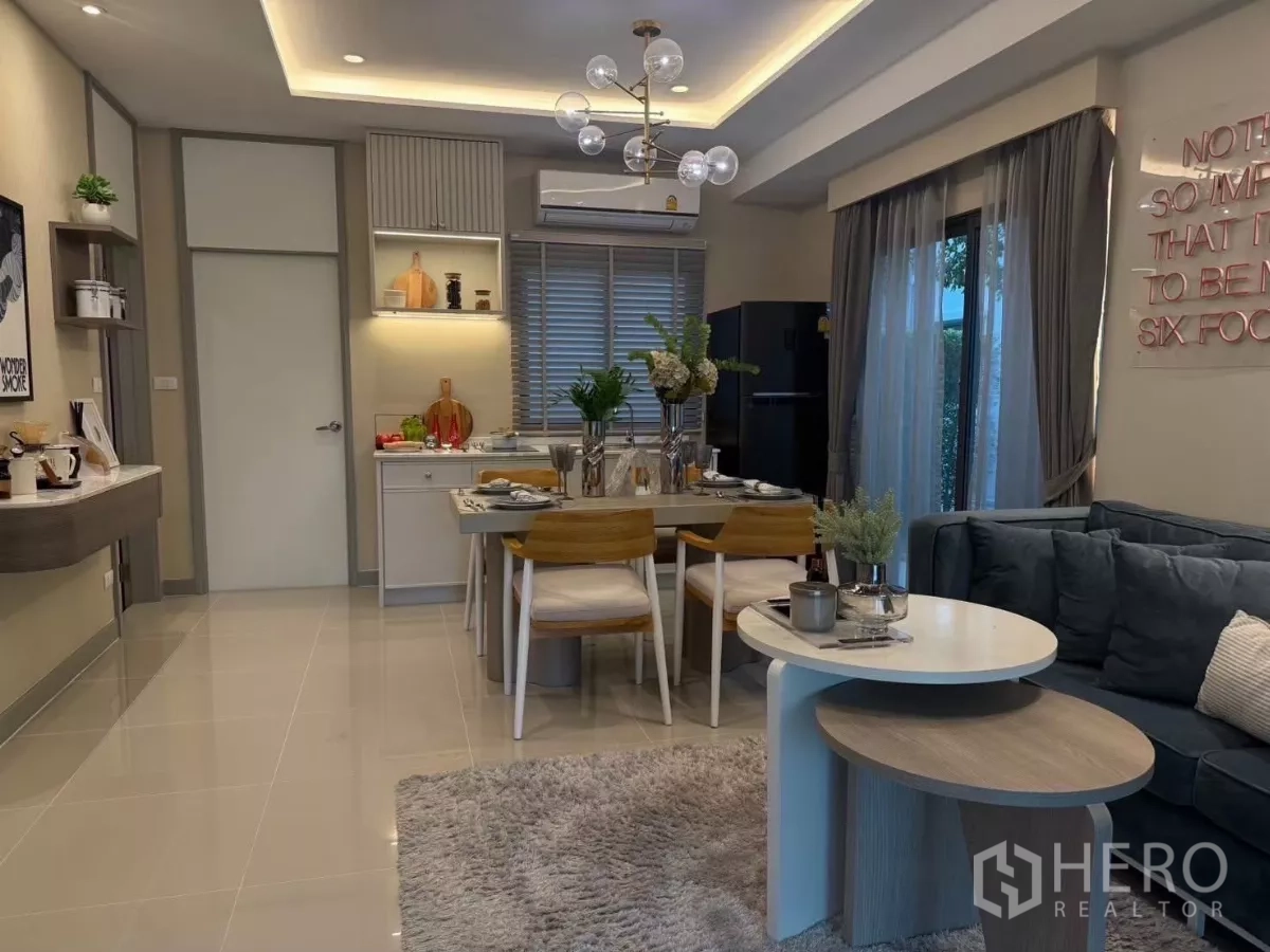 Townhouse for rent in Bang Phli, Samut Prakan - Open-plan living and dining room with chandelier, sofa and sliding glass door to the garden.