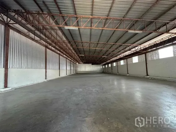 Warehouse for rent in Nakhon Pathom - Open-span warehouse hall with metal roof, ventilation blocks and smooth concrete flooring.