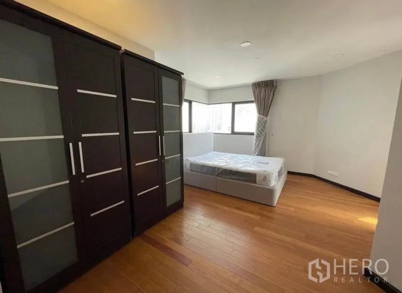 Condominium for rent - Large bedroom with dark wardrobes and corner windows.