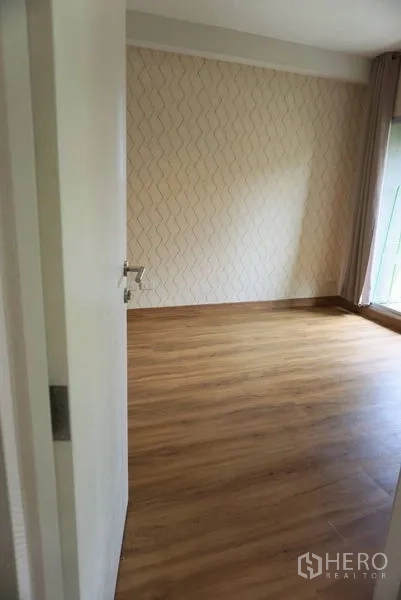 Condominium for sale in Khlong Toei, Bangkok - Corner of the bedroom with patterned feature wall, wood floors and large window.